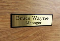 a name plate on a wooden door that says bruce wayne manager