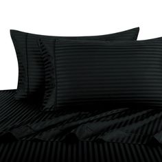 a bed with black striped sheets and pillows