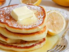 a stack of pancakes with butter and lemons on the side are ready to be eaten