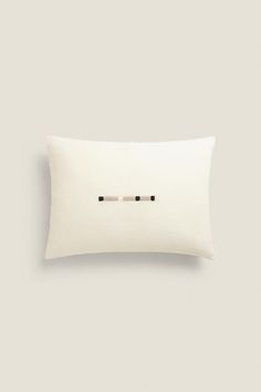 a white pillow with two black pins on the front and back of it, against a light gray background