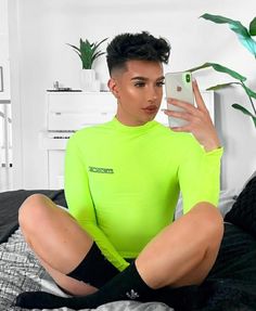 a person sitting on a bed with a cell phone in their hand and wearing a neon green shirt