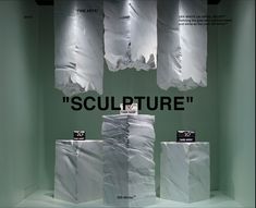 there is a display with white bags on the wall and black text above it that says,'sculpture '