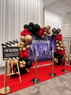 a red carpeted area with black and gold balloons in the shape of hollywood sign