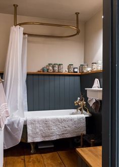 a bath tub sitting next to a wooden floor under a light hanging from the ceiling