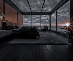 an empty bedroom with large windows overlooking the ocean at sunset or sunrise, is shown in black and white