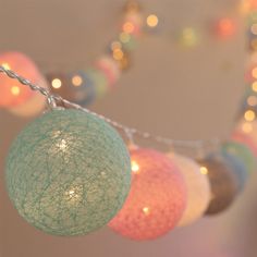 there are several balls hanging from the string with lights in the backgroung