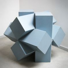 a blue sculpture sitting on top of a cement floor next to a white wall in an empty room