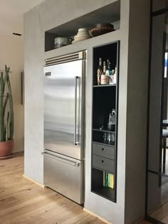 a stainless steel refrigerator and freezer combo in a kitchen with wood floors, built - in shelving