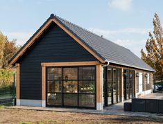 a small building with glass doors and a black roof