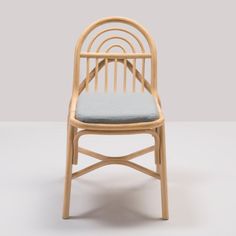 a wooden chair with a blue cushion on the seat and backrest, in front of a gray background