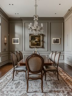 a dining room with a chandelier hanging from the ceiling and a rug on the floor