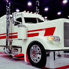 a white semi truck with red stripes on it's side and lights above the cab