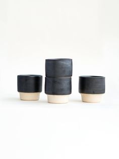 three black and white cups sitting next to each other on top of a white surface