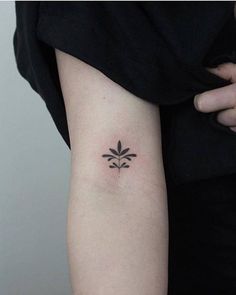 a woman's arm with a small flower tattoo on the back of her left arm