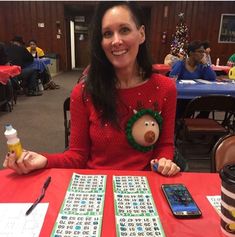 a woman sitting at a table with two christmas themed games on her lap and cell phones in front of her