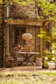 an outdoor table and chairs in front of a stone building with potted plants on it