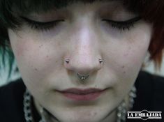 a close up of a person with piercings on their nose