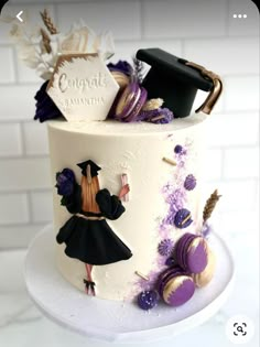 a white cake with purple and black decorations on the bottom layer, topped with an image of a graduate's cap