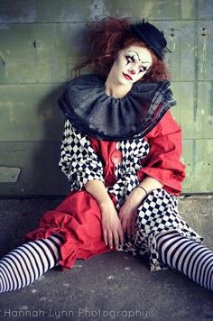 a woman dressed as a clown sitting on the ground