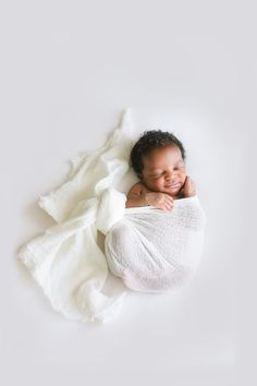 a smiling baby wrapped in a white blanket