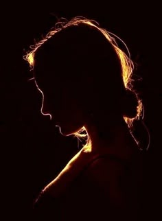 the silhouette of a woman's head is shown against a dark background with light coming through her hair