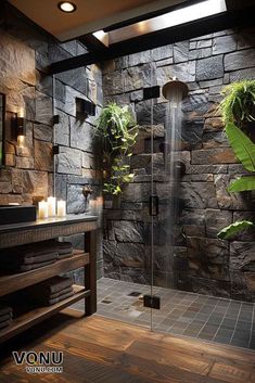 a bathroom with stone walls and flooring has a glass shower door that is open