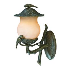 a lamp with a bird on it hanging from the side of a light fixture that is attached to a wall