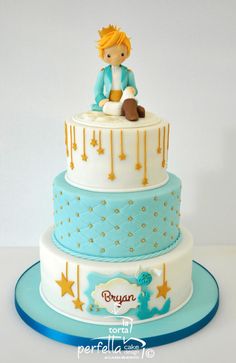 a blue and white cake with a boy sitting on top