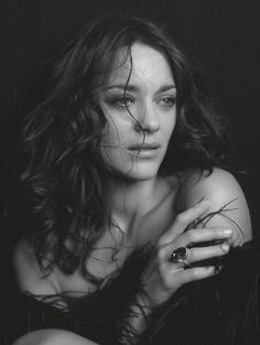 a black and white photo of a woman with long hair holding a ring in her hand