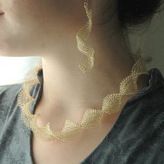 a close up of a person wearing a necklace and earring with leaves on it