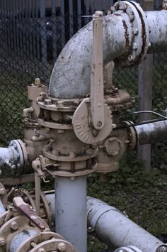 pipes and valves in front of a chain link fence