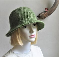 a mannequin head wearing a green hat with a deer antler on it