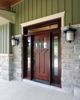 the front door to a house with two lights on each side and an entry way