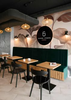 the interior of a restaurant with wooden tables and black chairs, white walls and paintings on the wall