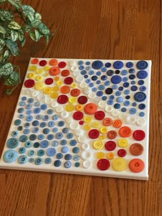 a wooden table topped with lots of different colored buttons and a potted plant next to it