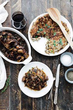 three plates with food on them sitting on a wooden table next to utensils