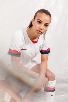 a woman kneeling down with her tennis racquet in front of her and the background is white