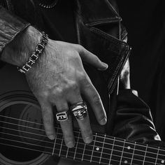 black and white photograph of a man's hand on top of an acoustic guitar