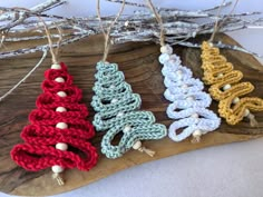 three crocheted christmas tree ornaments on a wooden board