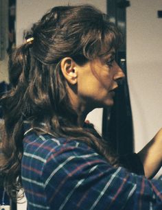 a woman holding a hair dryer in her right hand and looking at the mirror