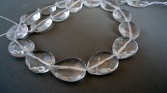 a close up of a necklace made out of clear glass beads on a black surface