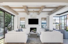 a living room with white couches and a flat screen tv mounted on the wall