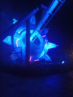 a large clock with blue lights on it's face in the dark night time