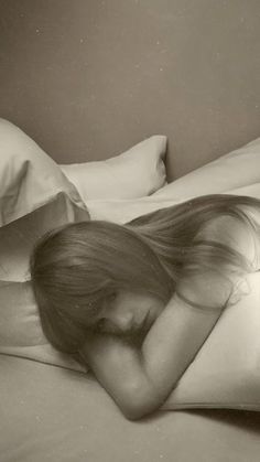 a black and white photo of a woman laying in bed with her head on the pillow