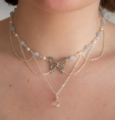 This necklace features delicate pastel blue beads, lustrous pearls, and draped chains, creating a layered, fairy and ethereal look. In the heart of this necklace, a captivating butterfly pendant and a sparkling clear crystal pendant add a touch of timeless beauty.  The layers of draped chains add depth and dimension to the necklace, allowing it to rest gracefully against your neckline, accentuating your natural beauty. The delicate nature of this piece ensures it is suitable for any occasion, from casual outings to formal events, making it a versatile addition to your jewellery collection. Elevate your style with this exquisite accessory, effortlessly blending sophistication with a touch of enchantment.  The pastel blue beads interspersed between the pearls create a harmonious colour palet Fairy Pearl Necklace, Ideas For Necklaces With Beads, Ethereal Jewelry Necklaces, Crystal Necklaces Ideas, Fancy Beaded Necklaces, Chain Necklace With Beads, Easy Bead Necklace, Necles Design