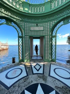 a woman is standing in an ornate archway by the water