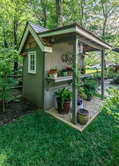 a small shed in the middle of a yard with potted plants and trees around it