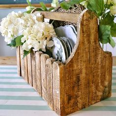 a wooden basket filled with white flowers on top of a blue and white striped table cloth