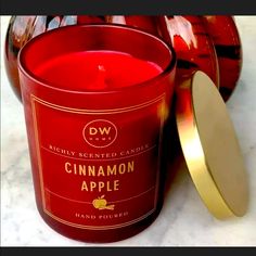 a red candle sitting on top of a counter next to a container with a lid