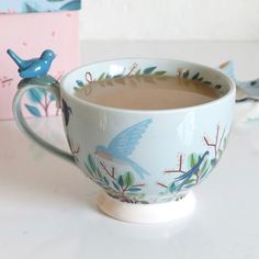 a cup of coffee with a bird figurine sitting on top of the cup